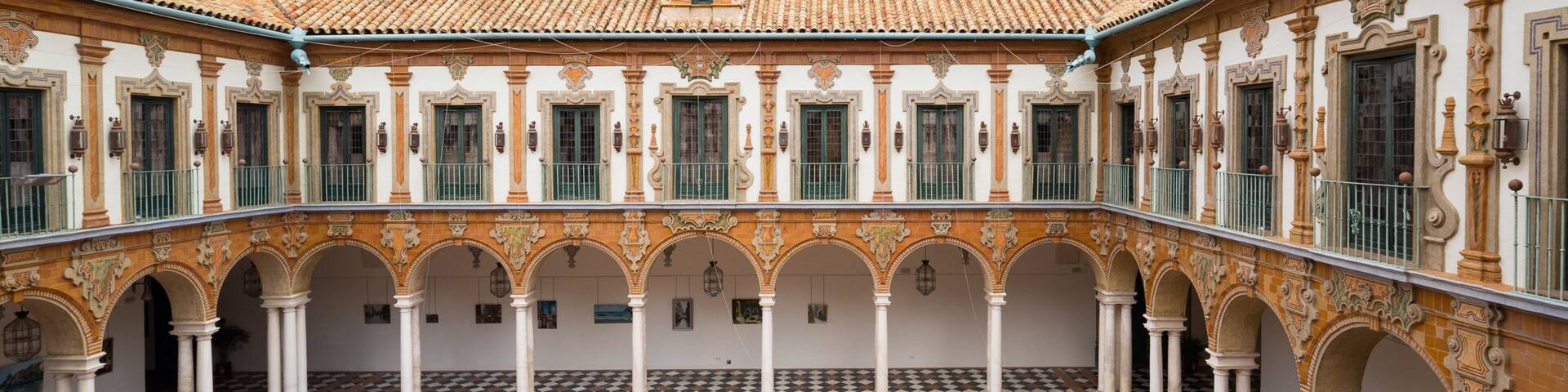 A courtyard with a fountain, tiled floor, and ornate columns.