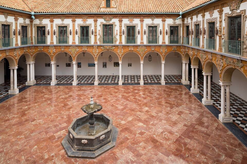 Un patio con una fuente, suelo de baldosas y columnas ornamentales.