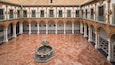 Une cour dotée d’une fontaine, d’un sol carrelé et de colonnes richement décorées.