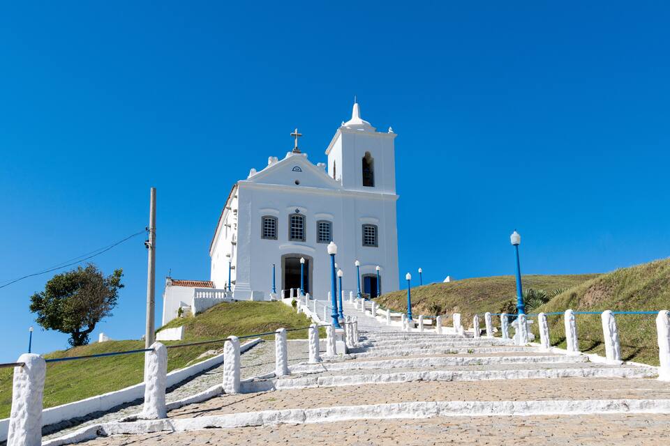 A white church with a bell tower, surrounded by a stone staircase and blue railings.