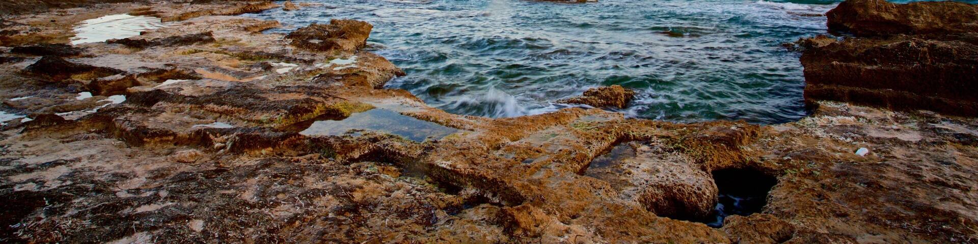 Banos de la Reina Archaelogical Site featuring a sunset, rocky coastline and general coastal views