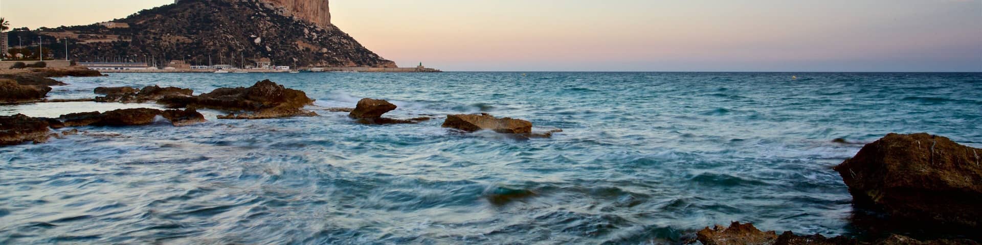 A coastal landscape with a prominent rock formation and calm sea.