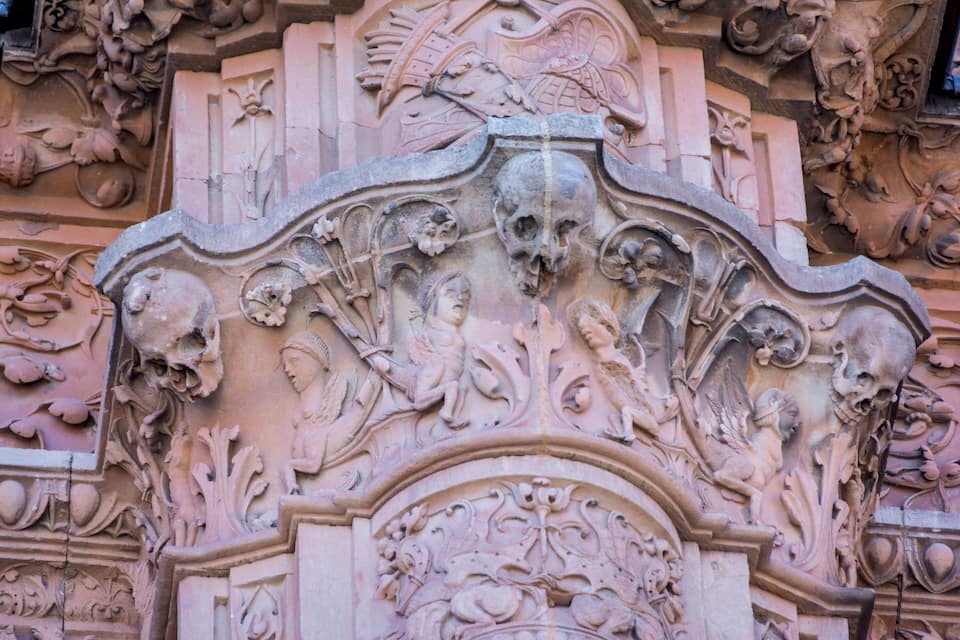 A detailed stone carving with skulls, cherubs, and floral motifs.