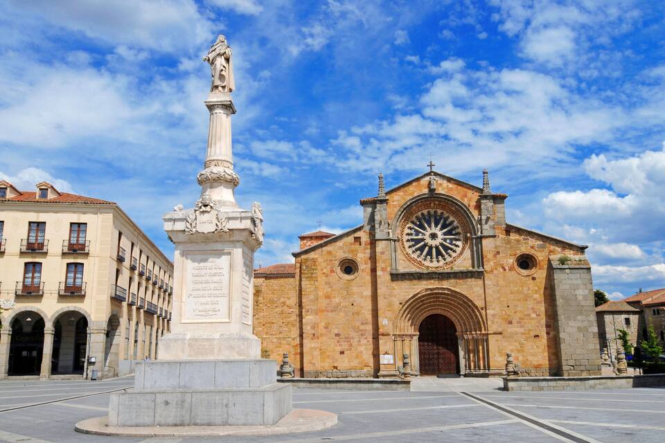 A historic church with a large clock and a monument in front.