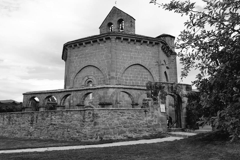 A historic stone building with a bell tower and arched windows.