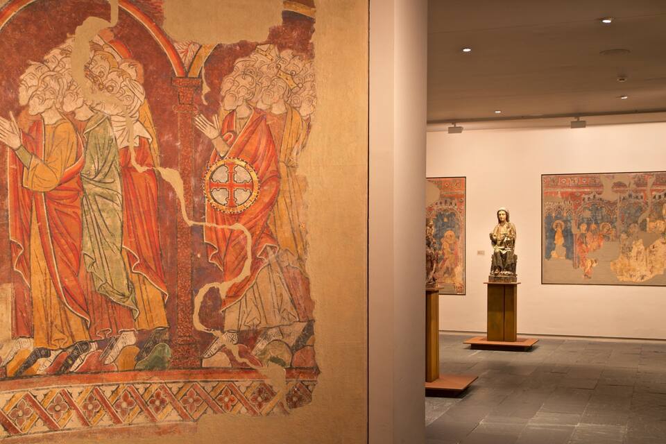 Een middeleeuws wandtapijt met religieuze figuren en een beeld van een heilige.