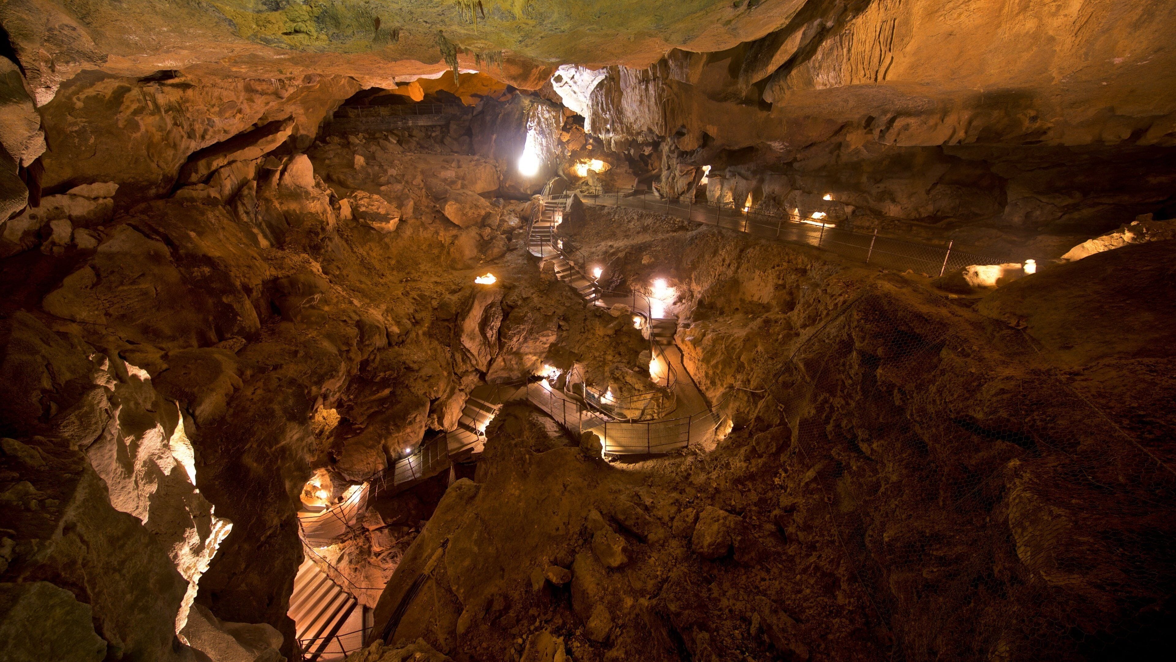 A cave with illuminated pathways and stalactites.