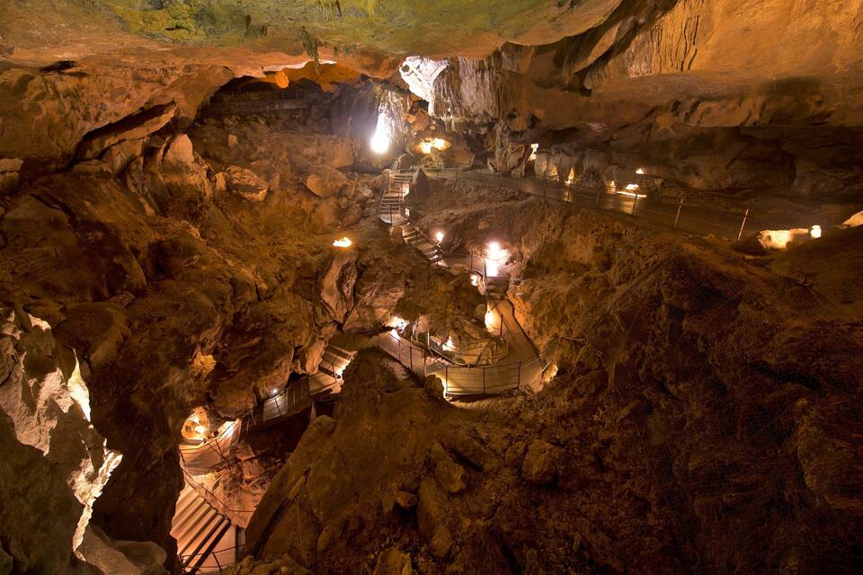 Una grotta con percorsi illuminati e stalattiti.