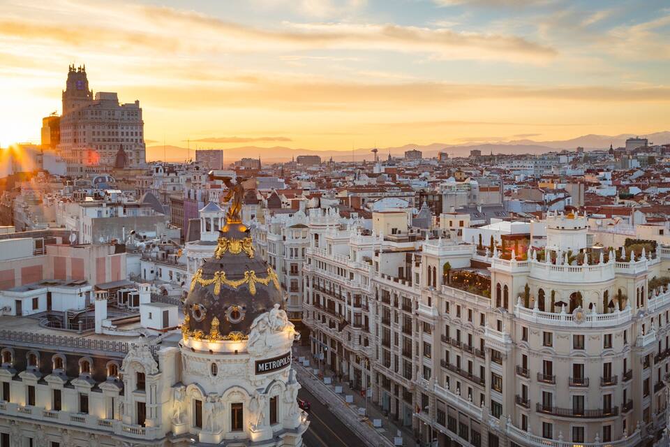 Vista urbana com um edifício imponente com uma cúpula dourada e a palavra 'METROPOLIS' em sua fachada.
