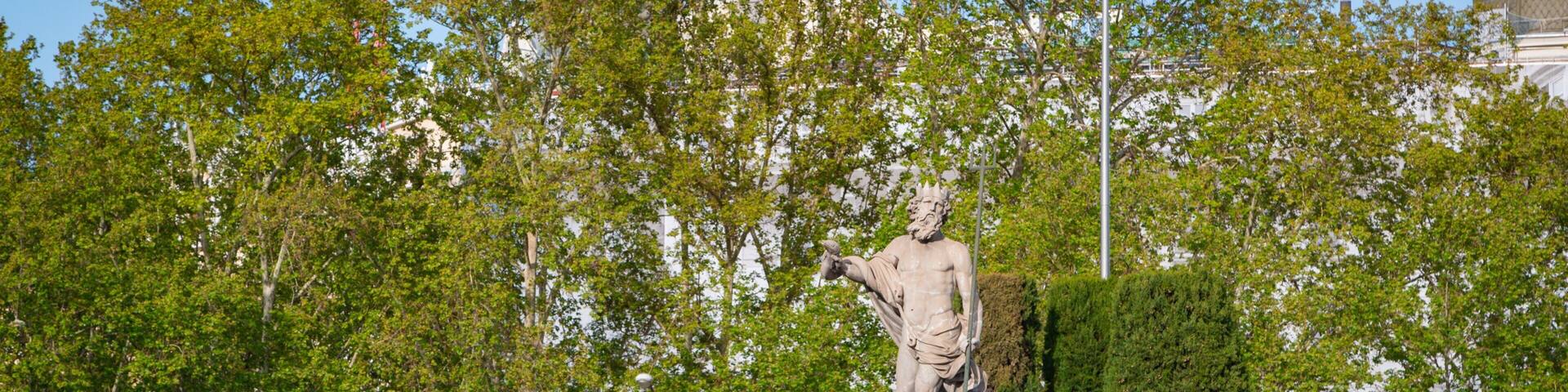 Fountain of Neptune featuring a statue or sculpture and a garden