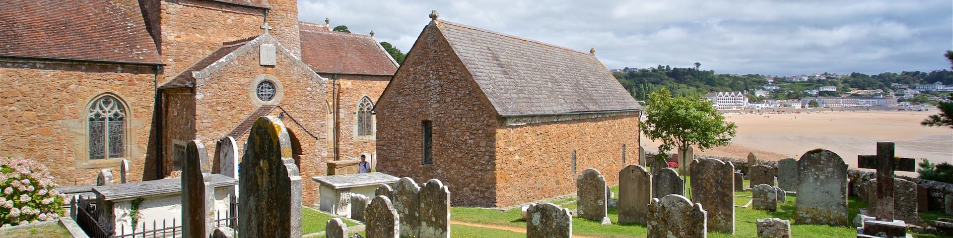 A church with a stone facade and a bell tower, surrounded by a cemetery with headstones.