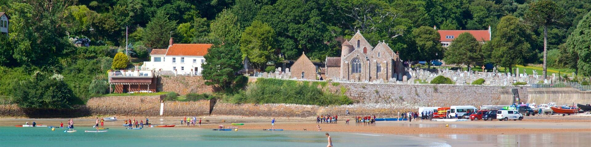 Parish Church of St. Brelade som visar en kuststad, en strand och kustutsikter