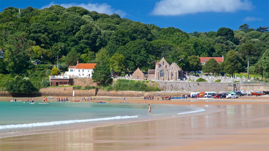 Parish Church of St. Brelade showing a sandy beach, general coastal views and a coastal town