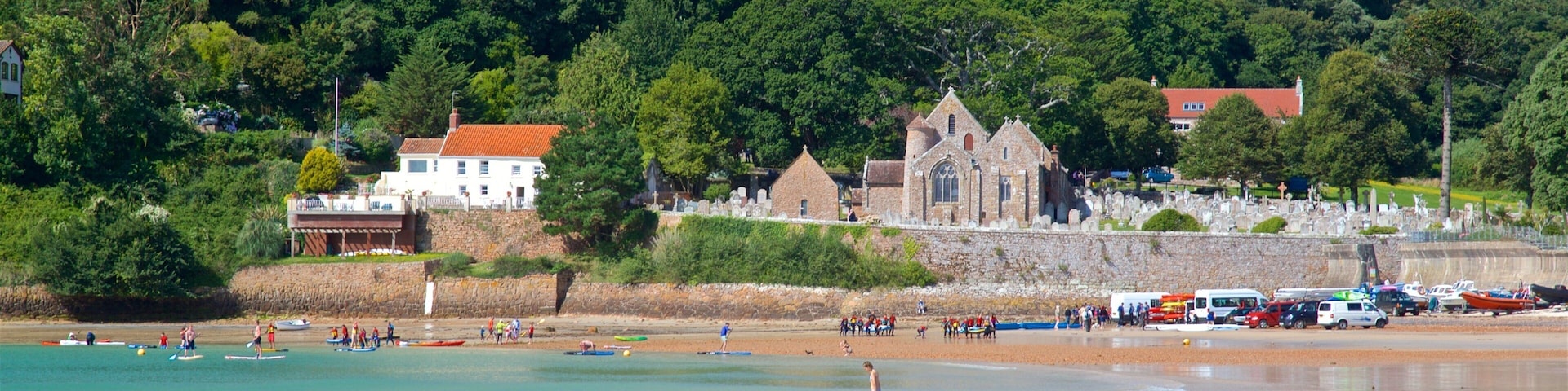 Parish Church of St. Brelade which includes a sandy beach, a coastal town and general coastal views
