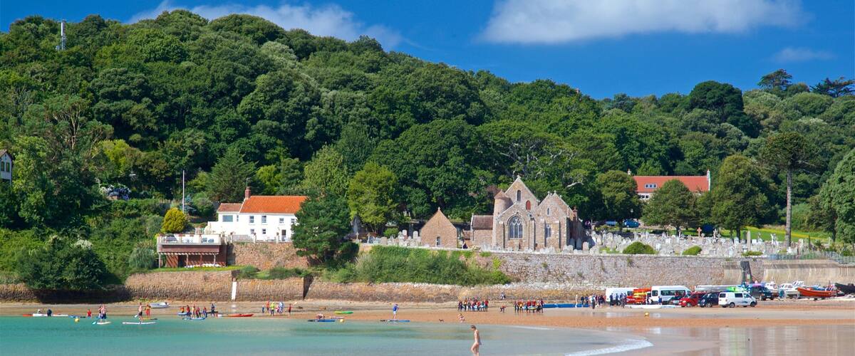 A beach with people surfing, a church, and a cemetery.