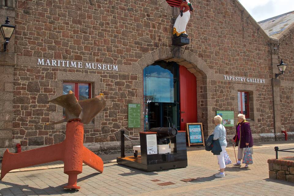 El Museo Marítimo y la Galería de Tapices, con un gran timón de barco y una estatua de una figura con un abrigo rojo.