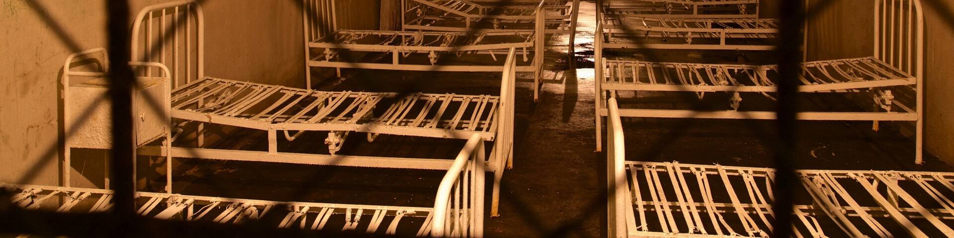 A series of bunk beds in a dimly lit, enclosed space with barred windows.