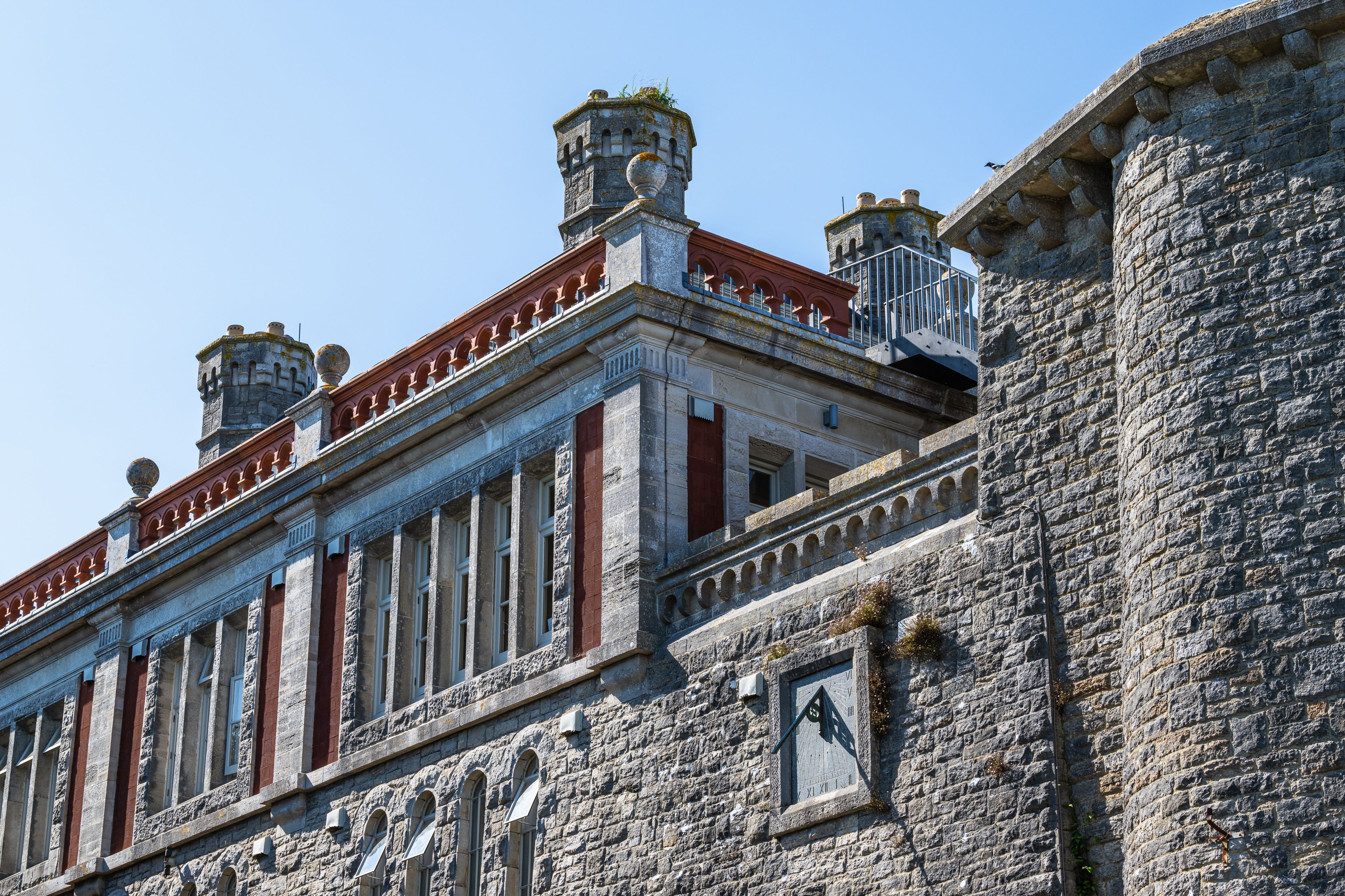 A historic building with stone walls, red and white trim, and a clock.