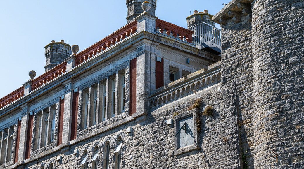 A historic building with stone walls, red and white trim, and a clock.