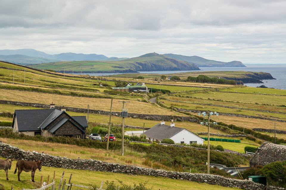 Rolling hills, a coastal view, stone walls, and traditional houses.