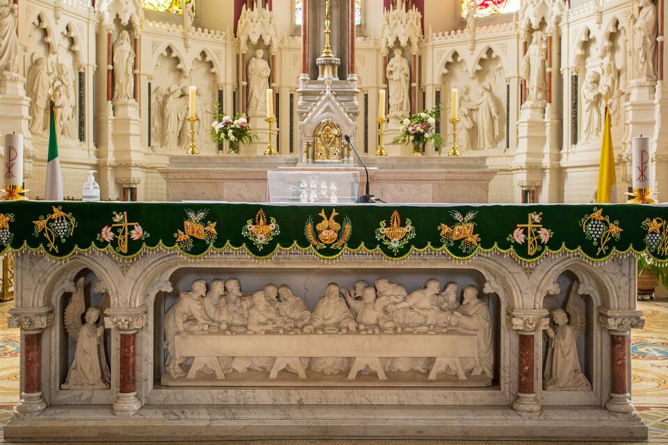 Un altar ornamentat amb talles religioses i un teixit verd amb borrons daurats.