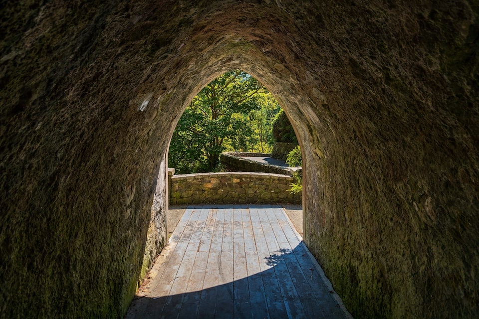 A stone tunnel with a wooden pathway leading through it.