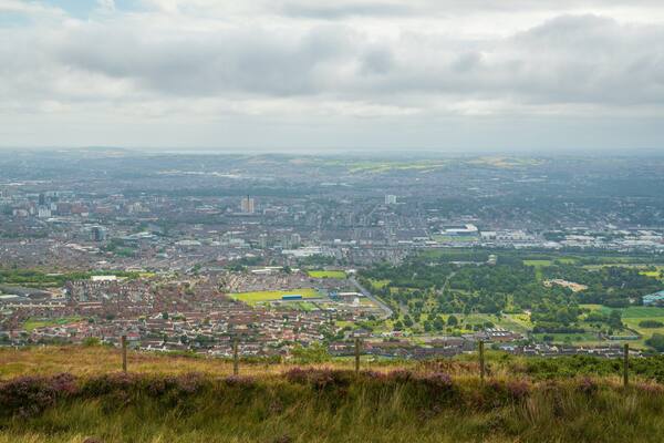 A panoramic view of a city with a mix of residential and commercial areas, a large stadium, and surrounding green fields.