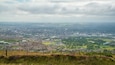 A panoramic view of a city with a mix of residential and commercial areas, a large stadium, and surrounding green fields.