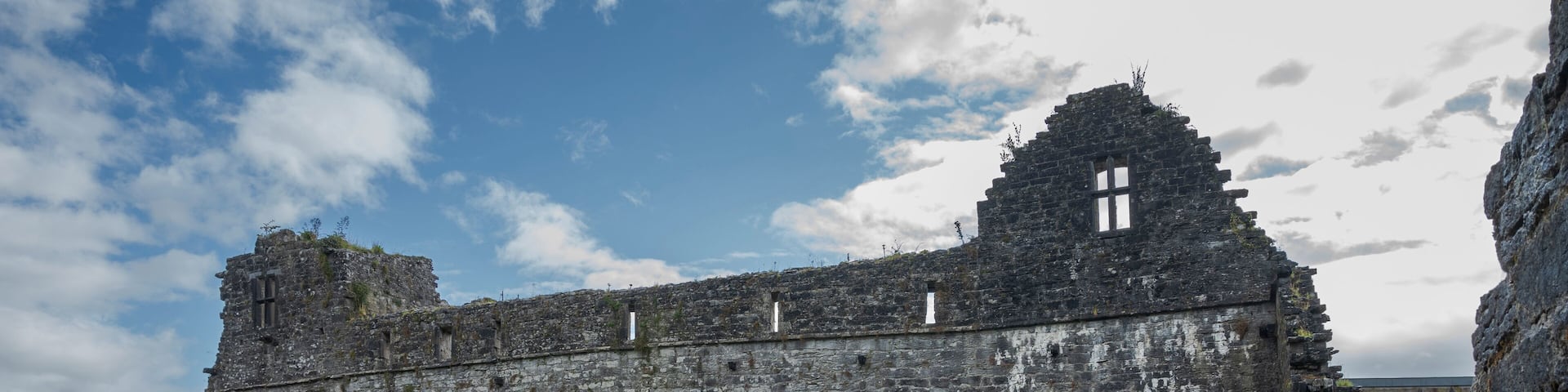 An ancient stone building with arched windows and a grassy courtyard.