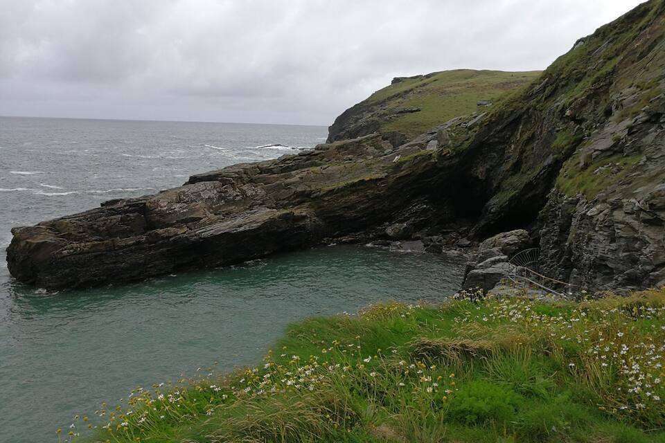 A rocky coastline with a grassy cliff and a body of water.