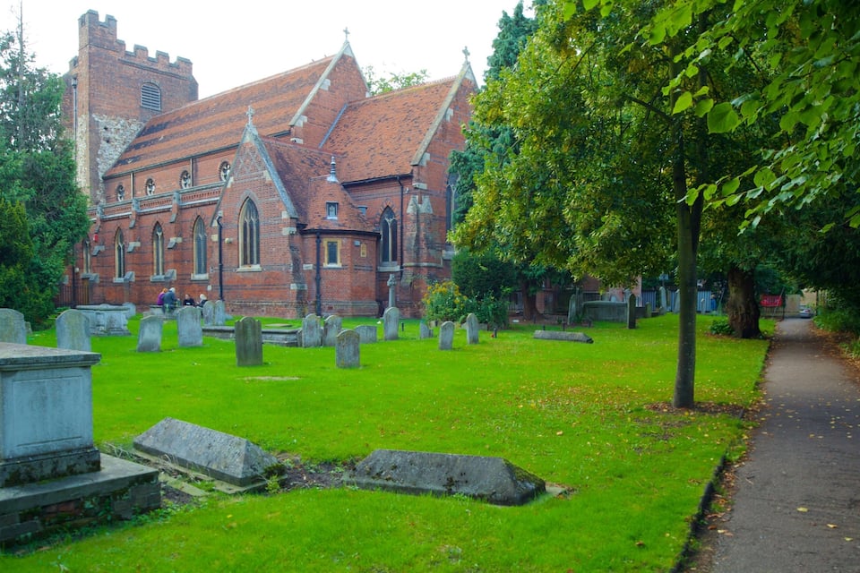 A church with a brick facade and a tower, surrounded by a cemetery with headstones.