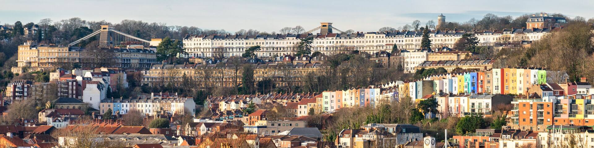 A cityscape with a prominent bridge, historic buildings, and a hill with a tower.