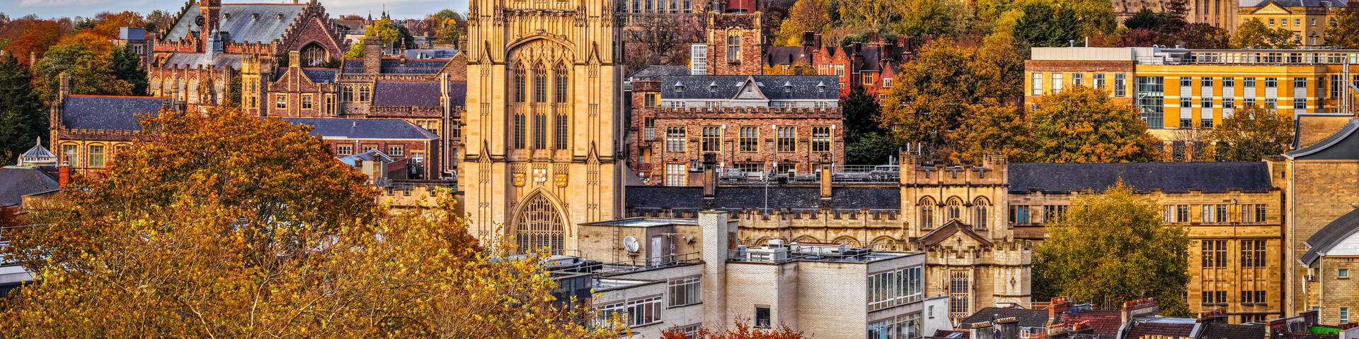 A historic cityscape with a prominent cathedral, traditional buildings, and autumn foliage.