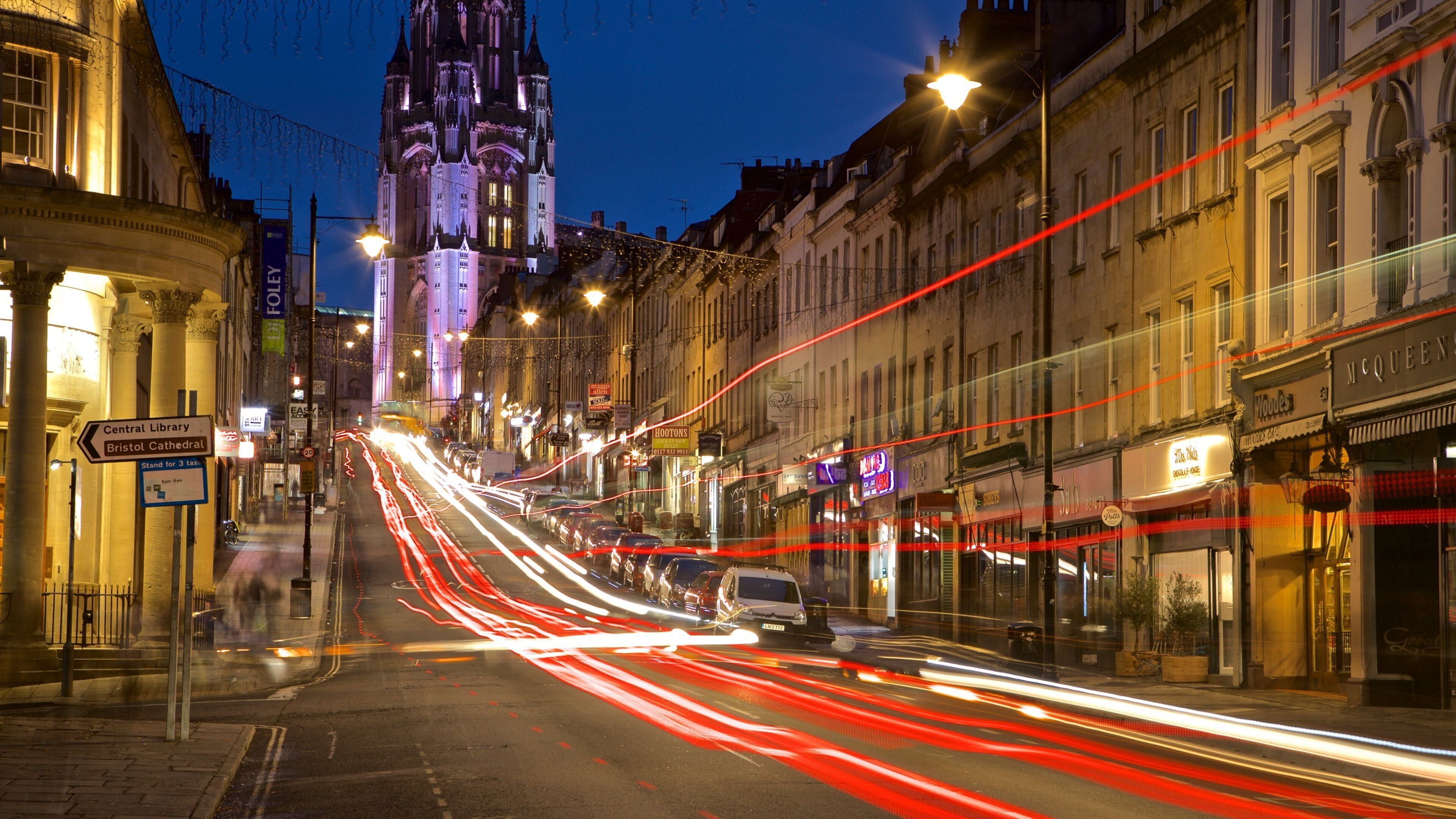 A city street at night with a historic building in the background.