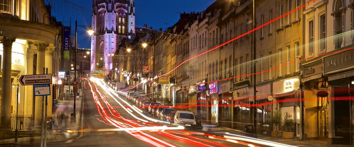A city street at night with a historic building in the background.