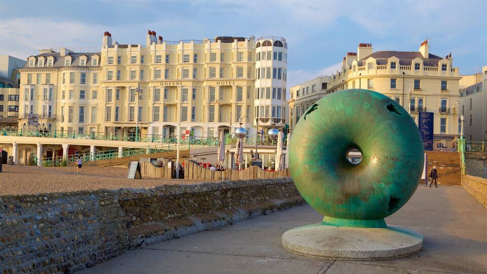 A large green sculpture on a promenade with historic buildings in the background.