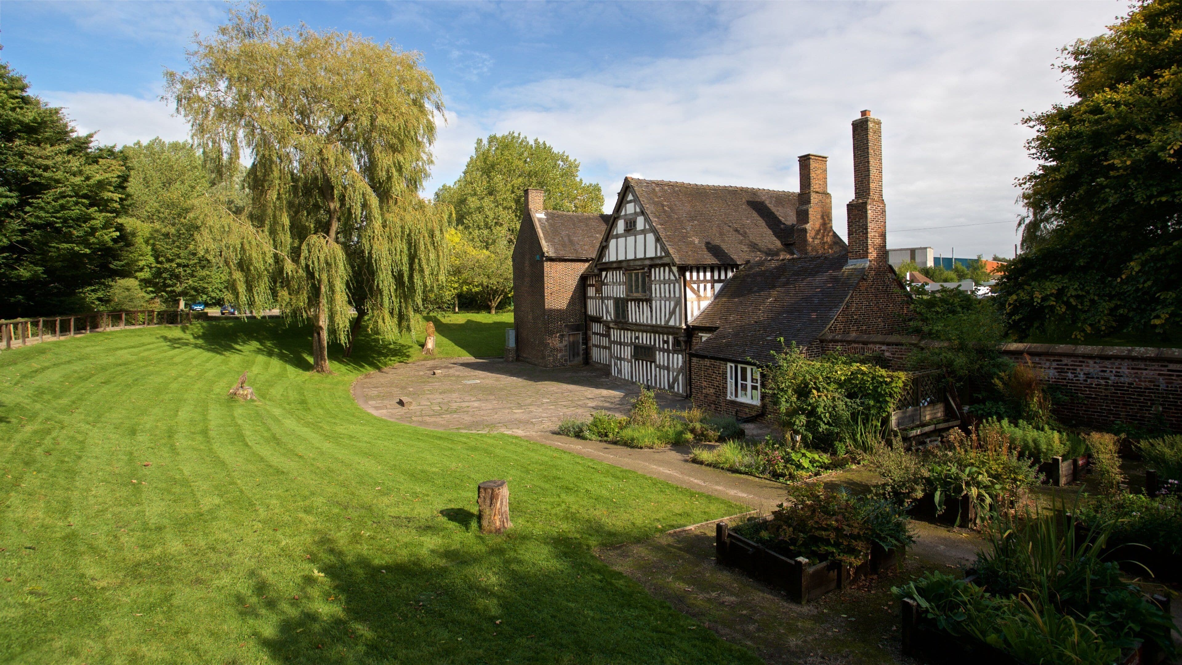 Ein Haus im Tudor-Stil mit einem gepflegten Rasen und einem großen Baum im Vordergrund.