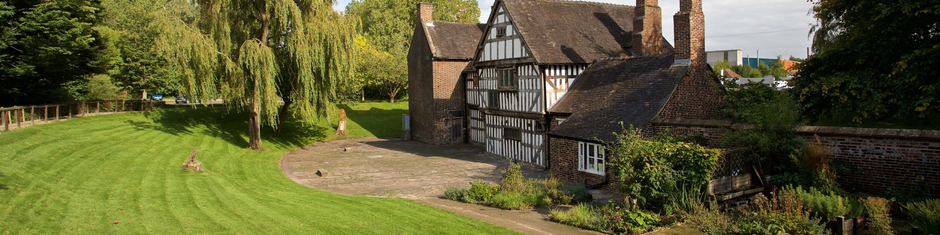 Uma casa em estilo Tudor com um gramado bem cuidado e uma grande árvore em primeiro plano.