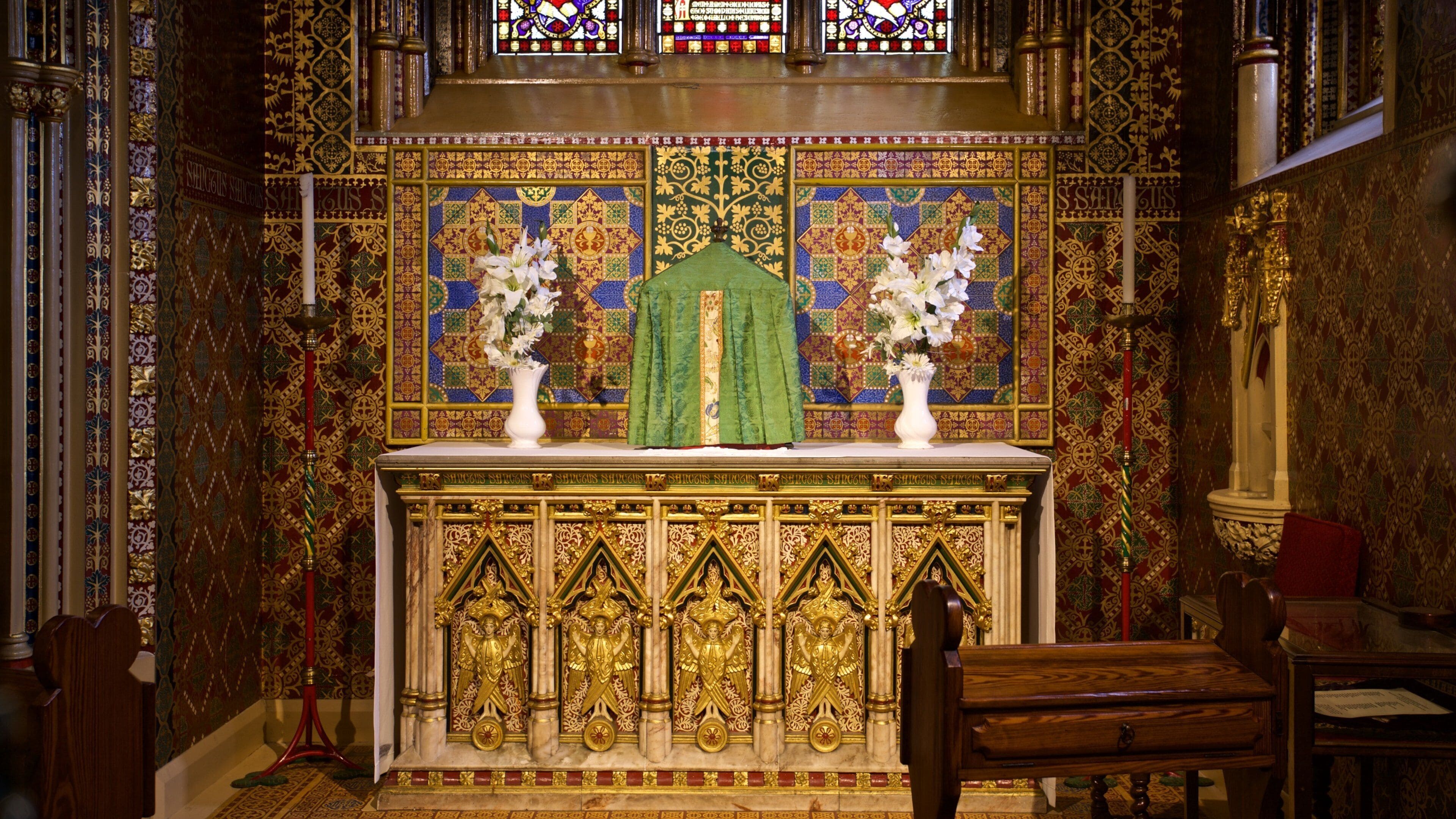 An ornate altar with religious icons, floral arrangements, and intricate wall designs.