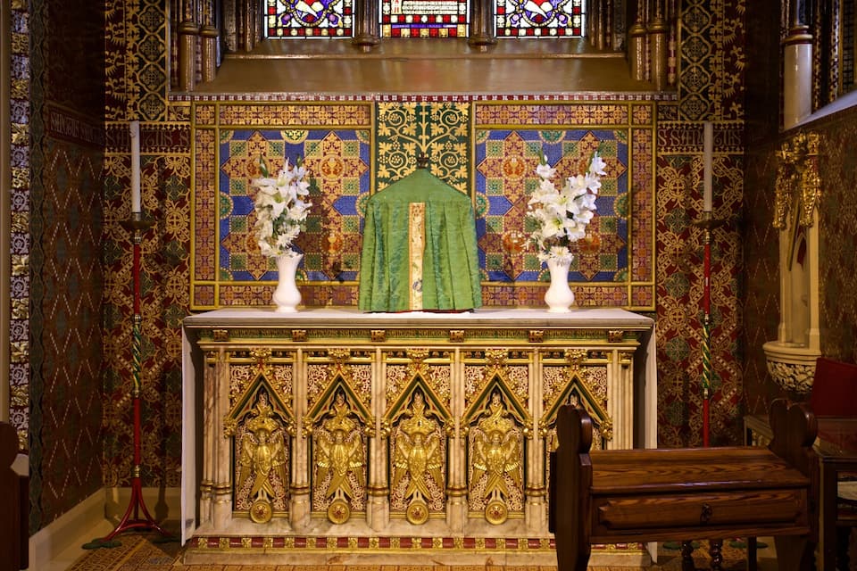 An ornate altar with religious icons, floral arrangements, and intricate wall designs.