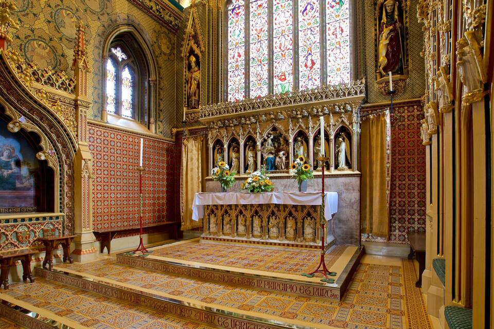 An ornate church interior with a high altar, stained glass windows, and intricate floor patterns.