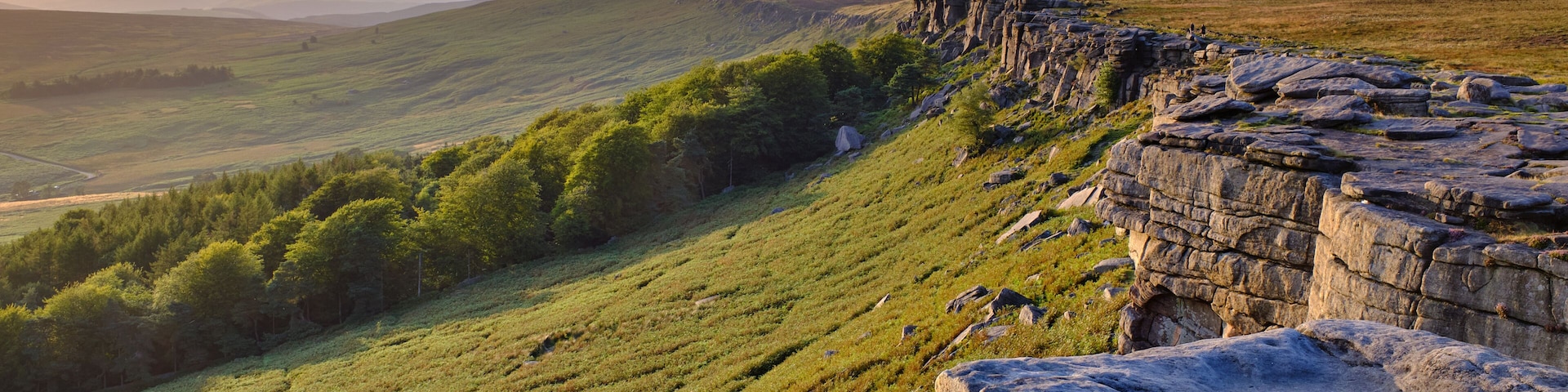 A grassy hillside with a rocky outcrop in the foreground.