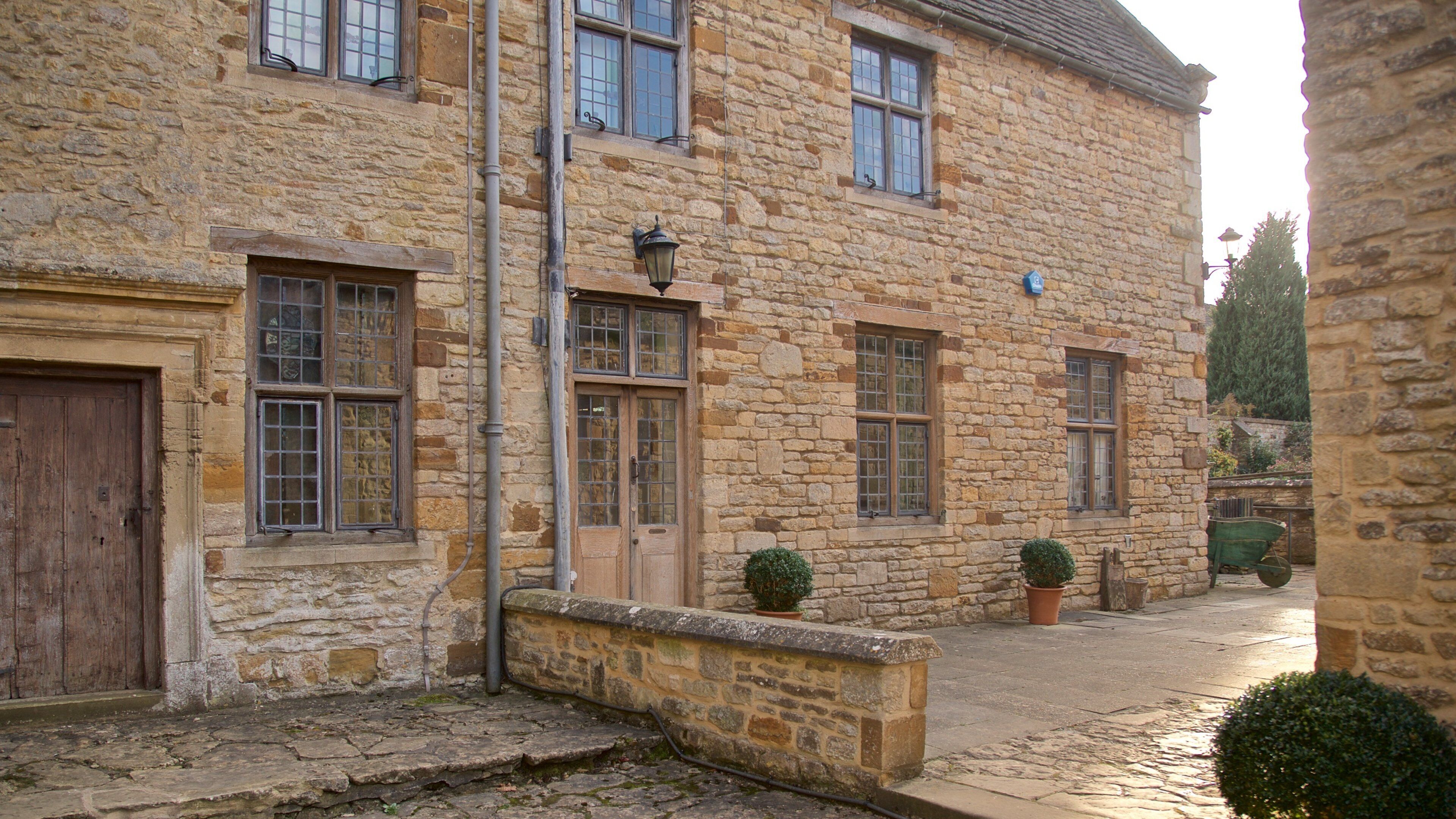 A stone building with multiple windows and doors, a cobblestone street, and potted plants.