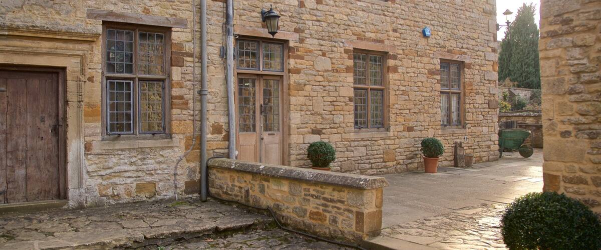 A stone building with multiple windows and doors, a cobblestone street, and potted plants.