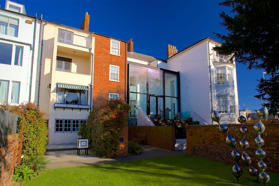 A residential area with modern and traditional houses, a well-maintained lawn, and decorative glass spheres.