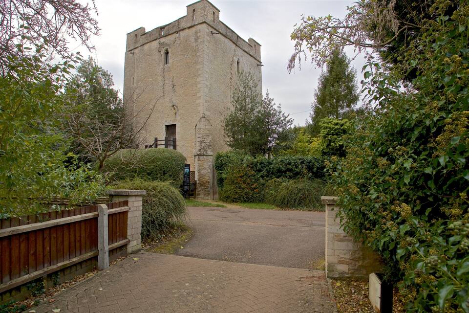 A stone tower surrounded by lush greenery and a wooden fence.