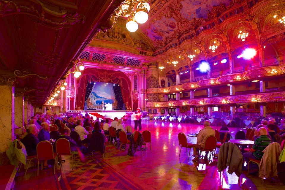 An ornate theater with a stage, audience, and elaborate ceiling decorations.