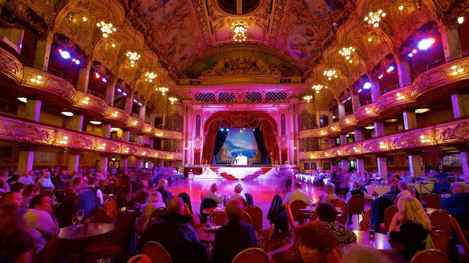 A grand theater with ornate architecture and a large audience seated.