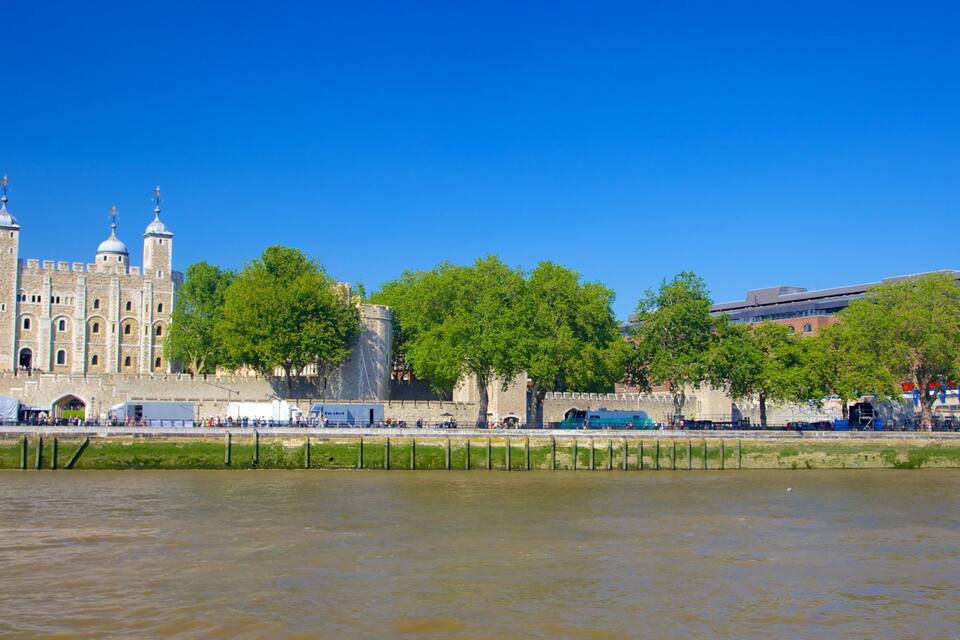 A historic castle with towers and a river in the foreground.