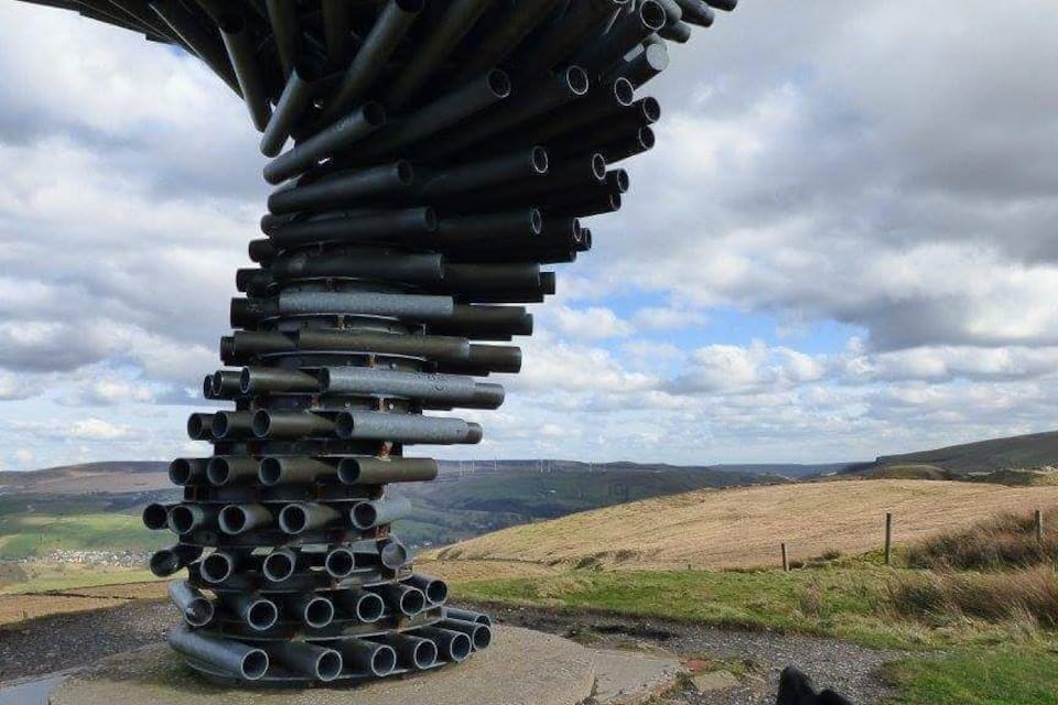 En skulptur af rør i et landskab.